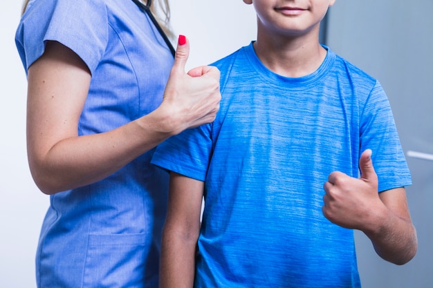 Foto gratuita dentista femminile con paziente che gesturing i pollici su