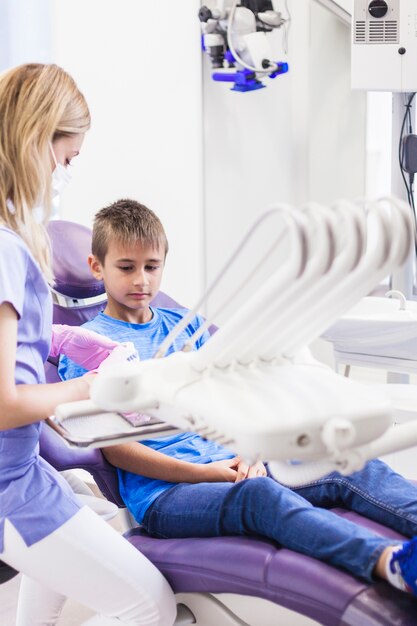 Женский стоматолог с зубами штукатурка плесень сидит возле ребенка пациента в клинике