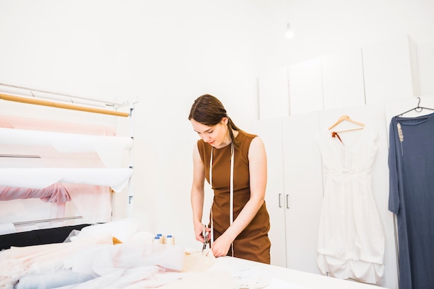 Female designer cutting fabric with scissors