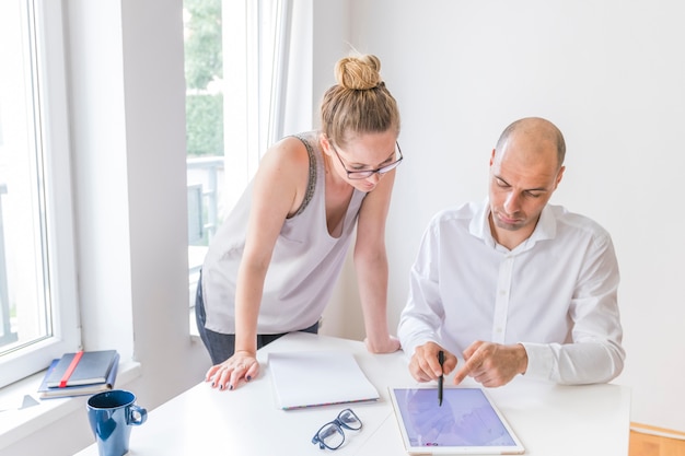 Free photo female designer looking at man showing with stylus on graphic digital tablet at workplace