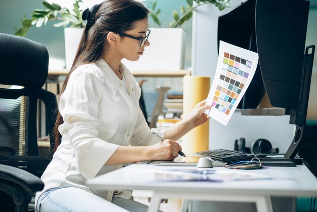 オフィスで見本を見ている女性のデジタルデザイナー
