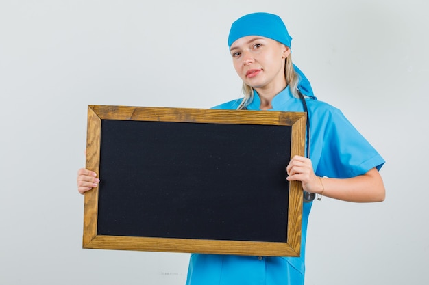 Female doctor in blue uniform holding blackboard and smiling