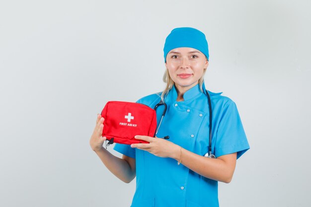 Female doctor in blue uniform holding first aid kit and looking cheerful