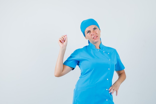 Dottoressa in uniforme blu che misura qualcosa di minuscolo e guardando pensieroso, vista frontale.