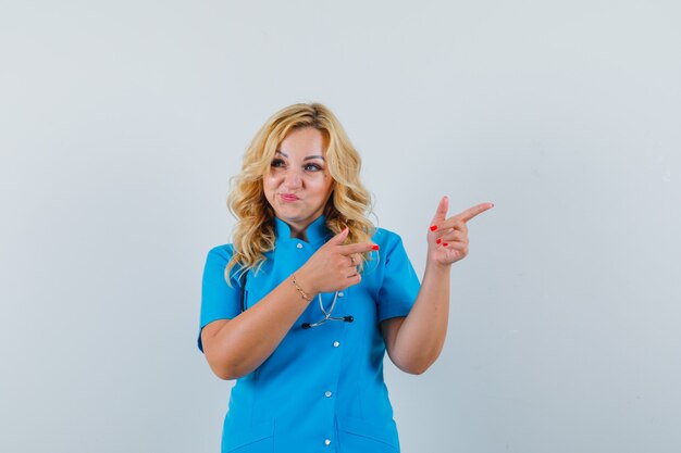 Female doctor in blue uniform pointing aside and looking confident