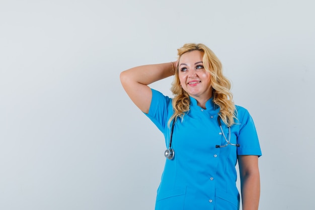 Female doctor in blue uniform posing with hand on head