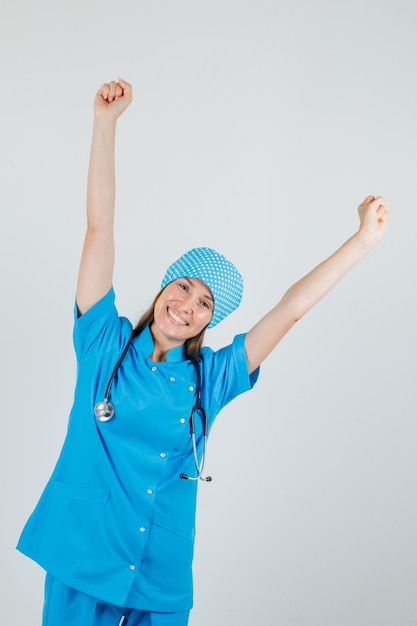 Medico femminile in uniforme blu che alza i pugni e che sembra allegro