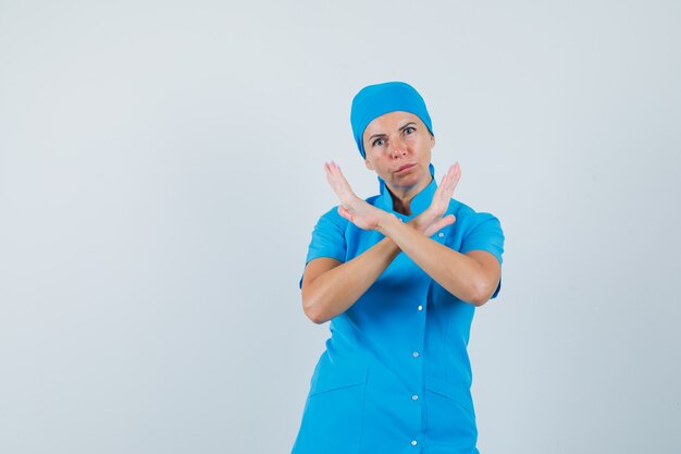 Female doctor in blue uniform showing refusal gesture and looking serious , front view.