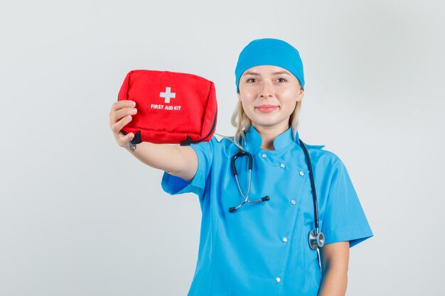 青い制服を着た女医が救急箱を見せて元気そうに見える