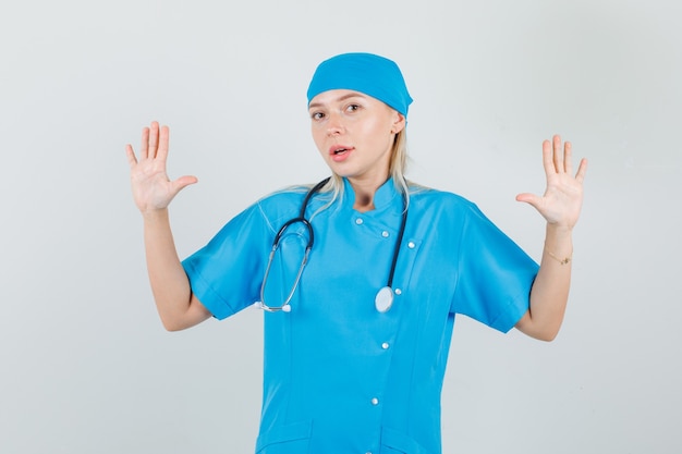 Female doctor in blue uniform showing up open palms and looking confident 