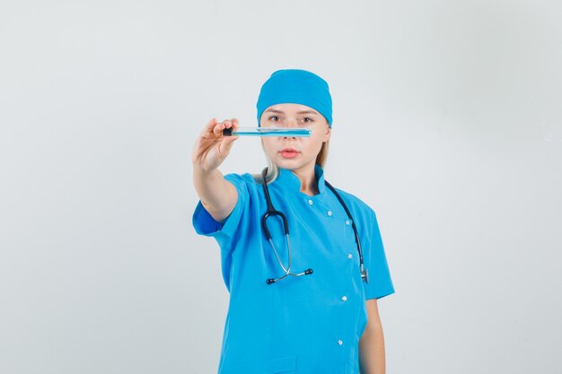 Female doctor in blue uniform showing up test tube 