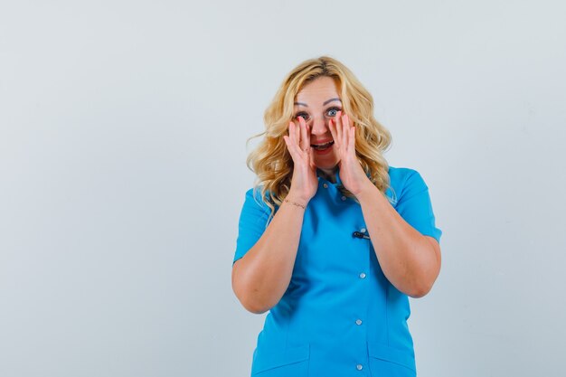 Female doctor calling someone with loud voice in blue uniform and looking hopeful space for text