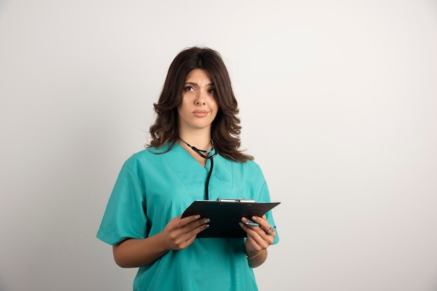 Female doctor carrying important document on clipboard.