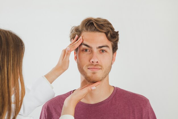 Female doctor checking face of male patient