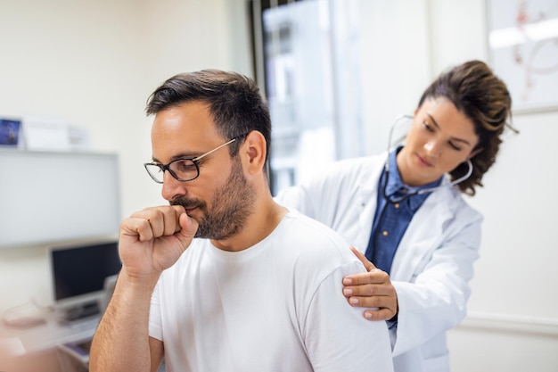 A female doctor at the clinic performs auscultation of the lungs of a patient with symptoms of coronavirus or pneumonia