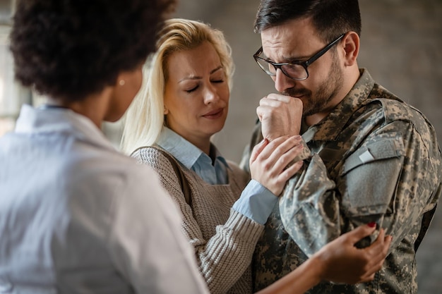 Женщина-врач утешает плачущего ветерана и его жену после получения плохих новостей в медицинской клинике В центре внимания солдат