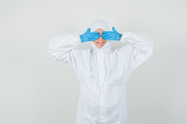 Female doctor covering eyes with hands in protective suit