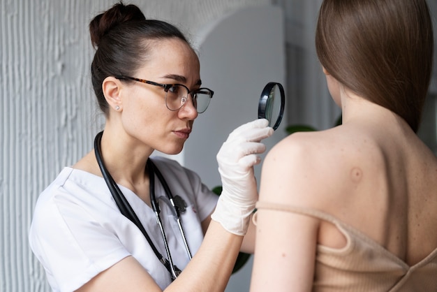 Female doctor diagnosing a melanoma on the body of a female patient