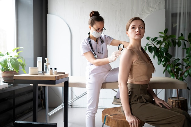 Female doctor diagnosing a melanoma on the body of a female patient