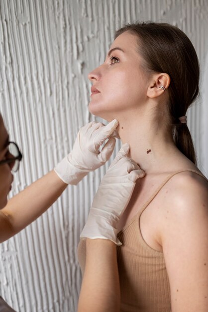 Female doctor diagnosing a melanoma on the body of a female patient