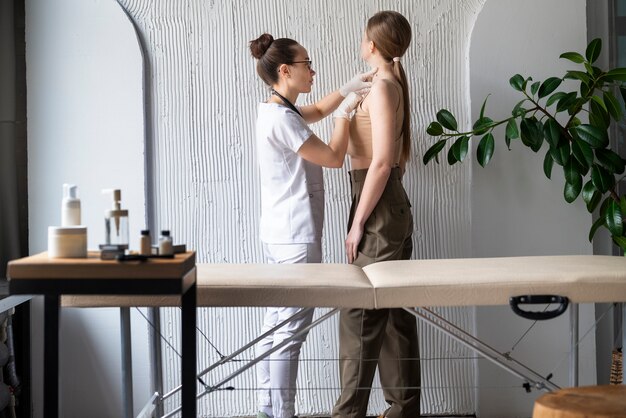 female doctor diagnosing a melanoma on the body of a female patient