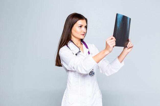 Женский доктор рассматривая изображение рентгеновского снимка изолированное на белой стене.