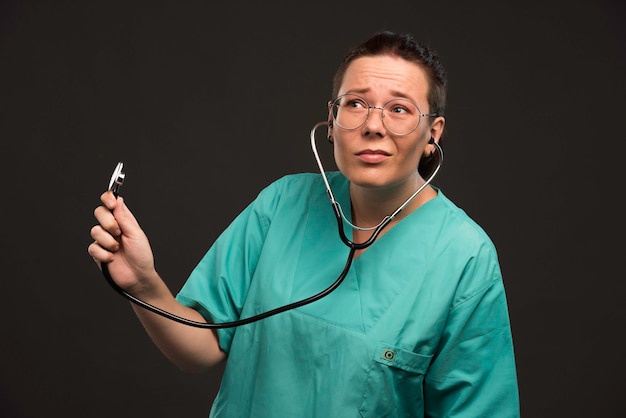 Female doctor in green uniform holding a stethoscope and listening the patient. 