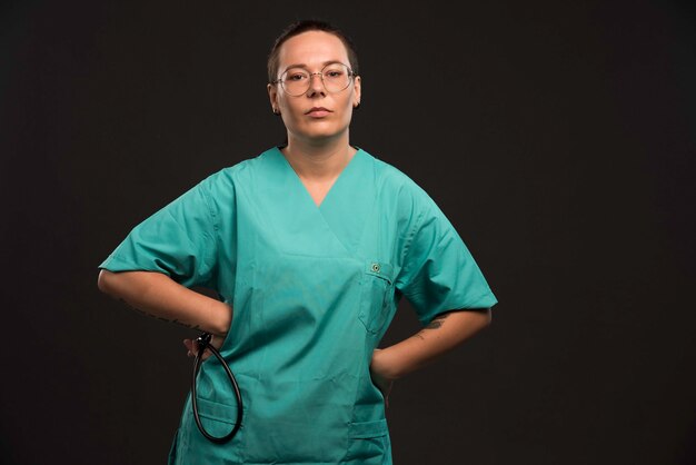 Female doctor in green uniform holding a stethoscope. 