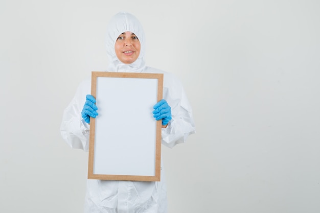 Женщина-врач держит пустую рамку в защитном костюме