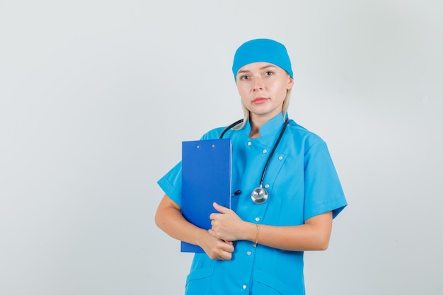Женщина-врач держит буфер обмена в синей форме