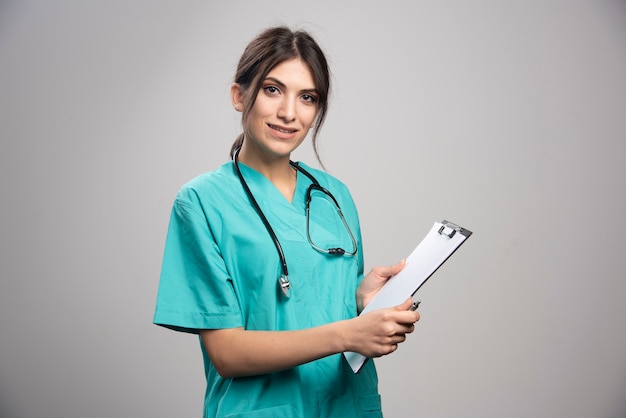 Female doctor holding clipboard on gray