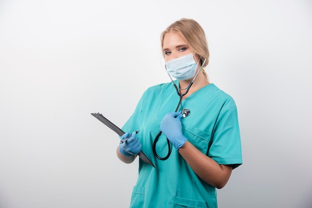 Female doctor holding clipboard and wearing a medical mask. High quality photo