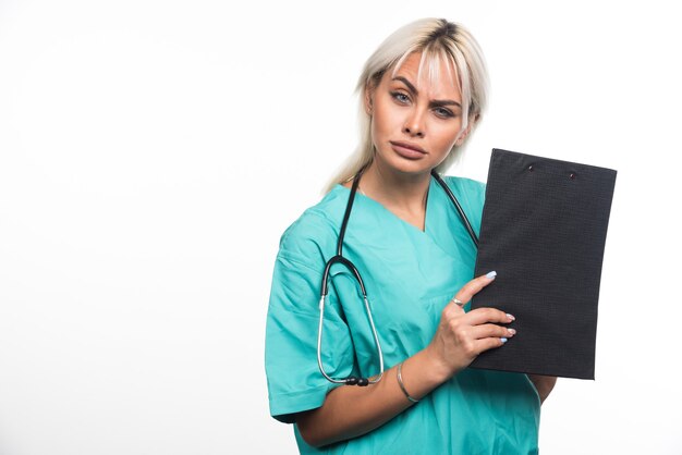Female doctor holding a clipboard on white background looking serious. High quality photo