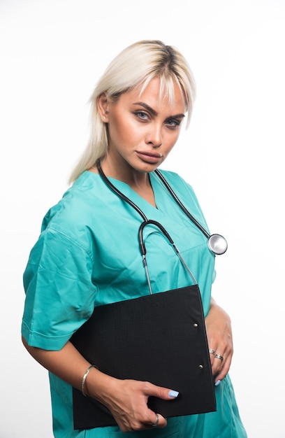 Free photo female doctor holding a clipboard on white background looking serious. high quality photo