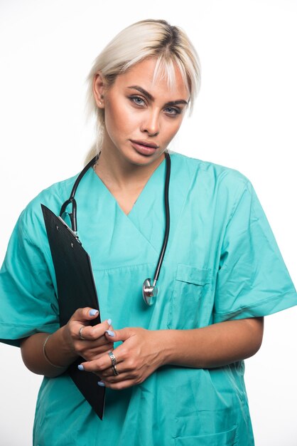 Female doctor holding clipboard on white surface