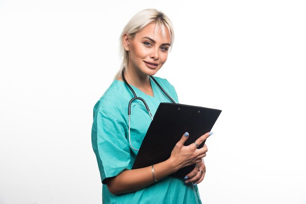 Female doctor holding clipboard on white surface