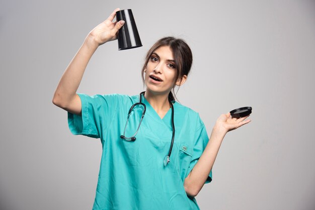 Female doctor holding cup of coffee on gray