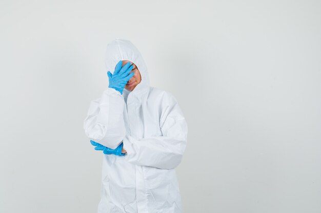 Female doctor holding hand on face in protective suit