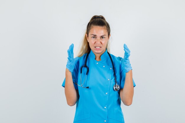 Female doctor holding hands in aggressive manner in blue uniform