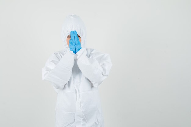 Female doctor holding hands in praying gesture in protective suit