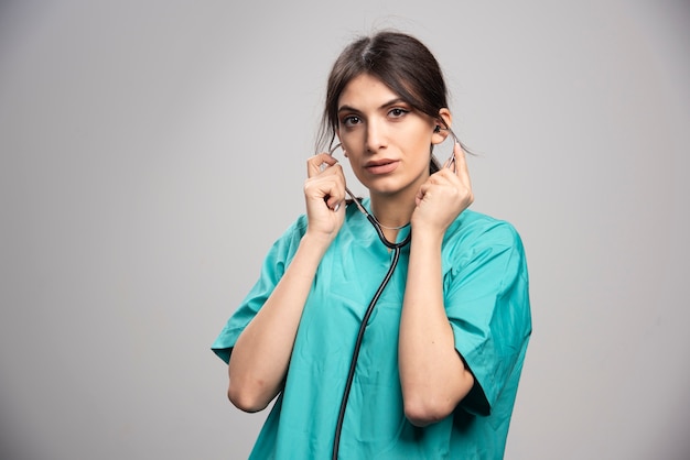 Female doctor holding stethoscope on gray