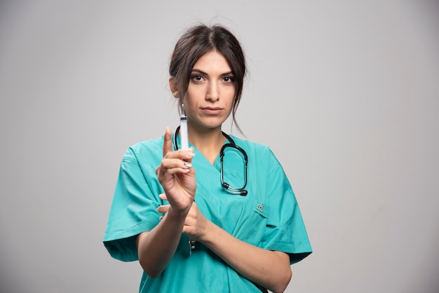 Female doctor holding syringe on gray