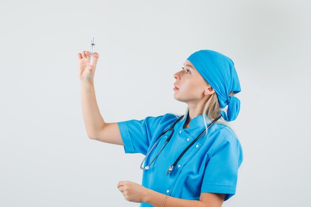 Female doctor holding syringe for injection in blue uniform