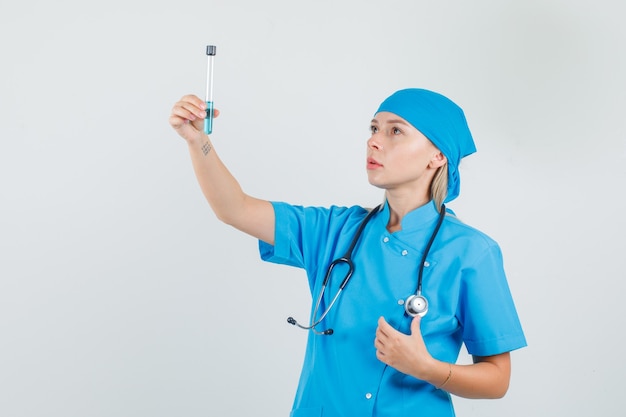 파란색 유니폼에 테스트 튜브를 들고 여성 의사