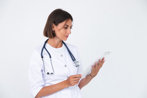 Женщина-врач в лабораторном халате на белом изолированной, уверенной улыбке держит белую бумагу