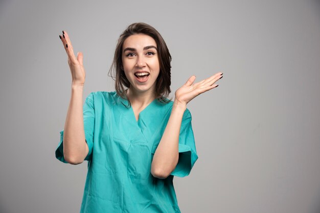 Female doctor laughing on gray wall.