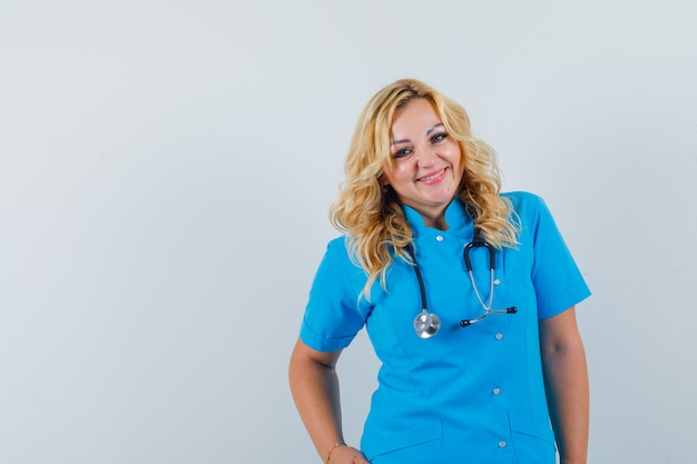 Female doctor looking at camera while smiling in blue uniform and looking glad.