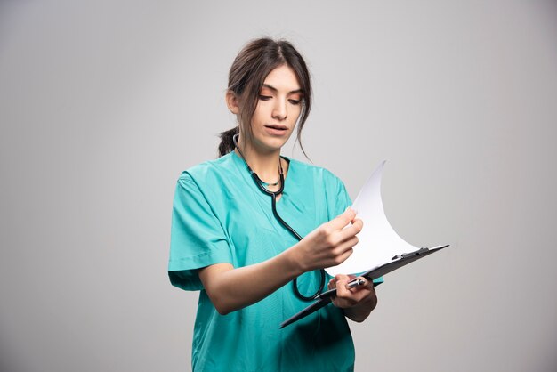 Female doctor looking at notes on clipboard