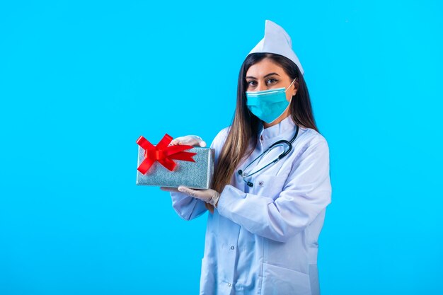 Female doctor in mask holding a gift box