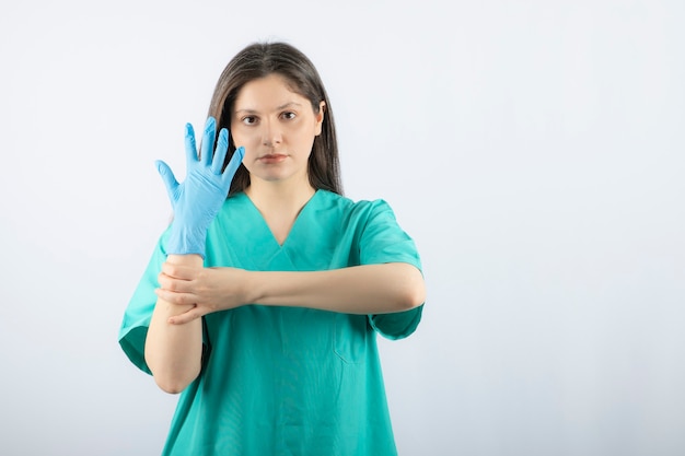 Female doctor in medical gloves showing hands on white. 